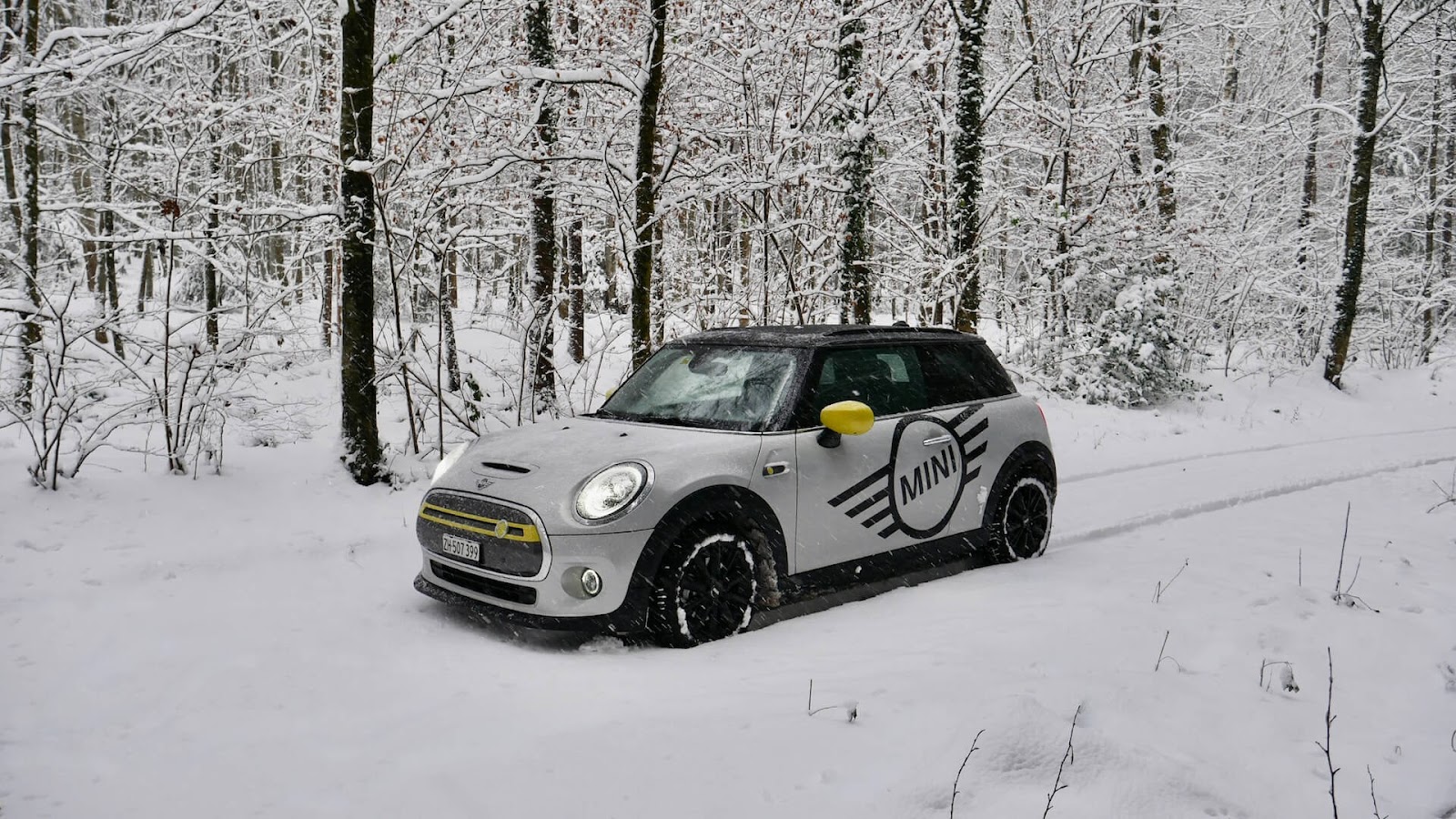 Electric Mini Cooper drives through the snow.