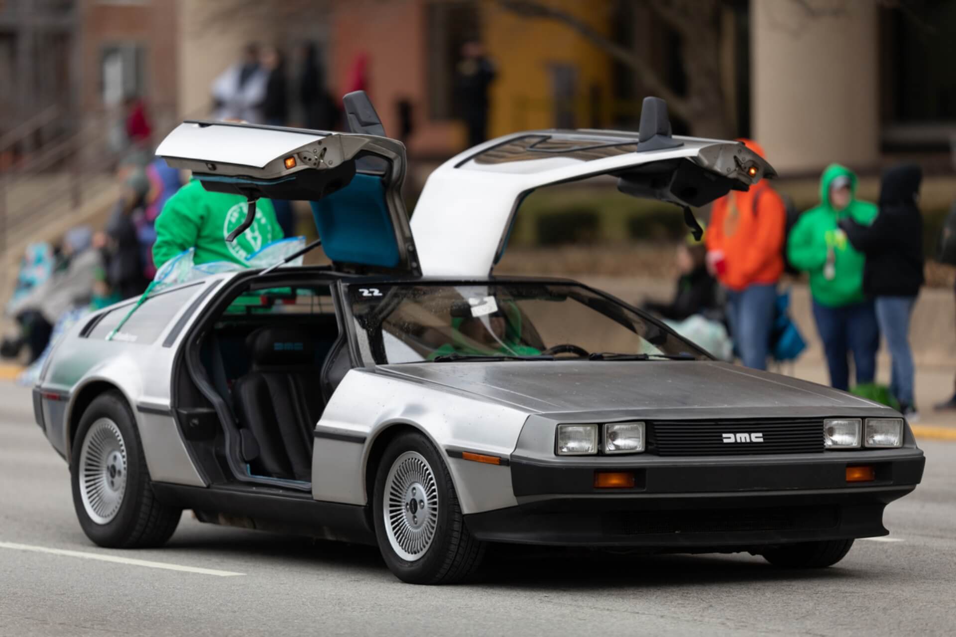 A DeLorean car on the street with the doors open.