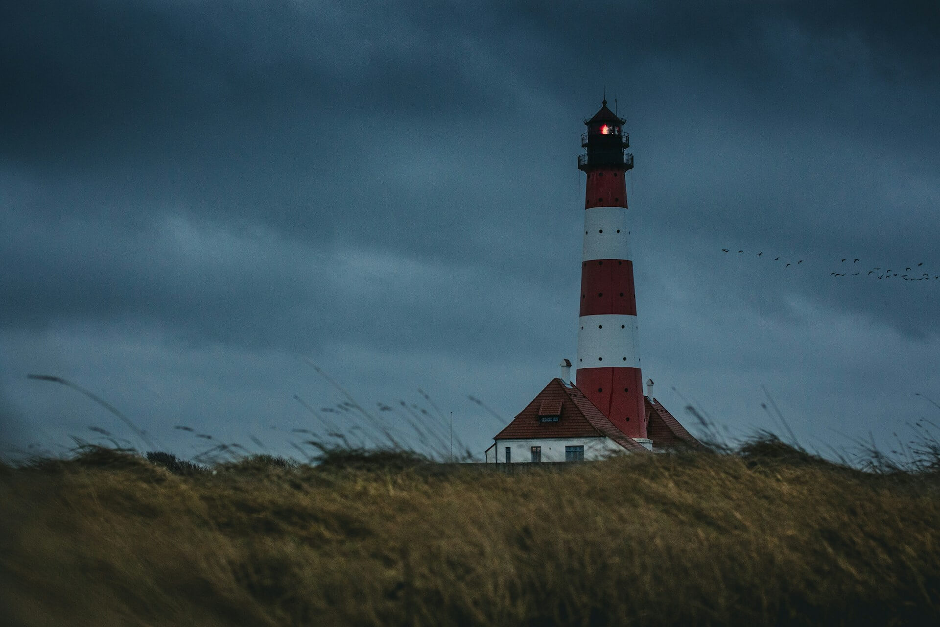 Lighthouse on a grassy hill on a cloudy evening
