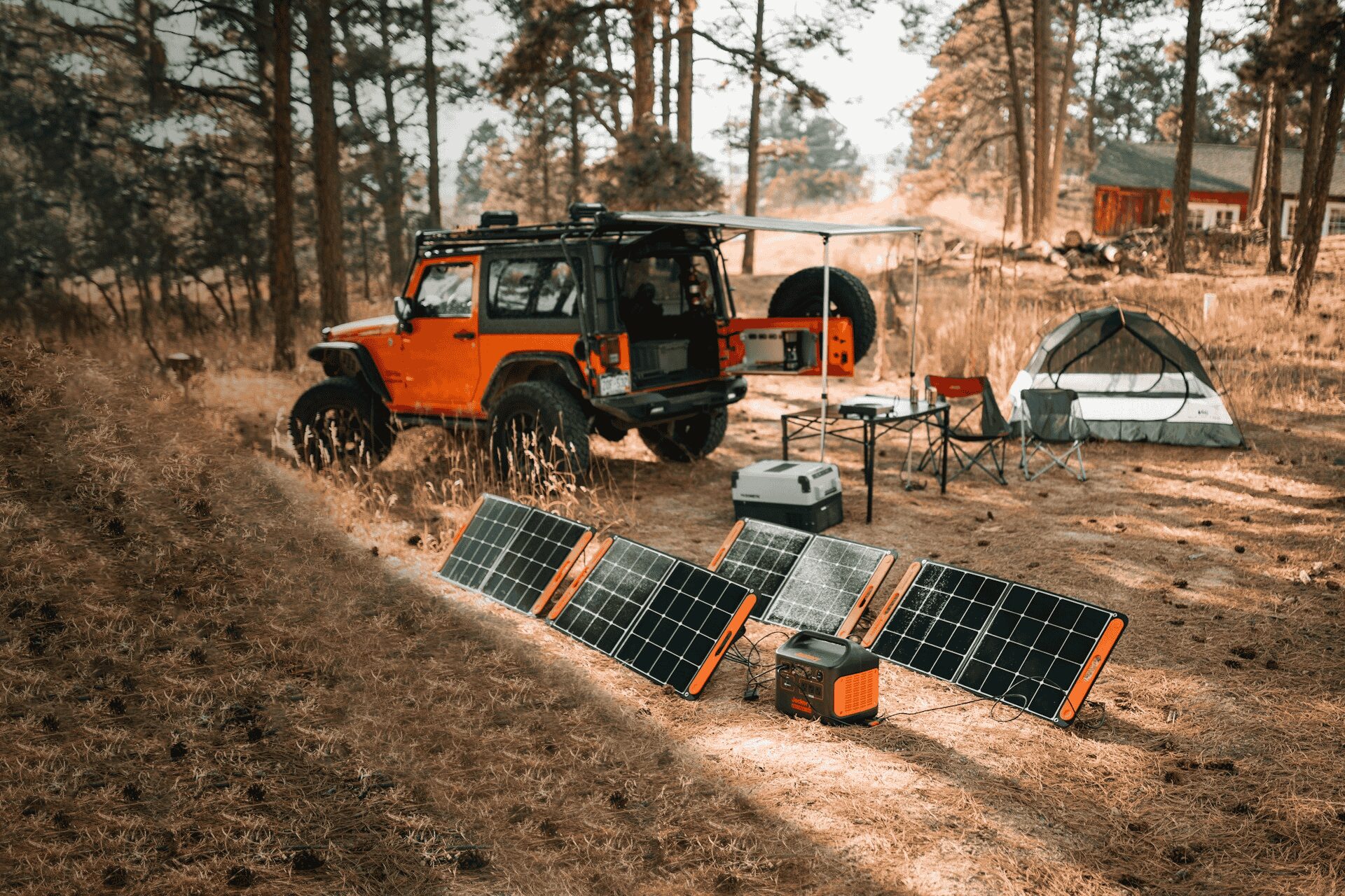 A truck on a campsite next to a tent and solar panels on the ground