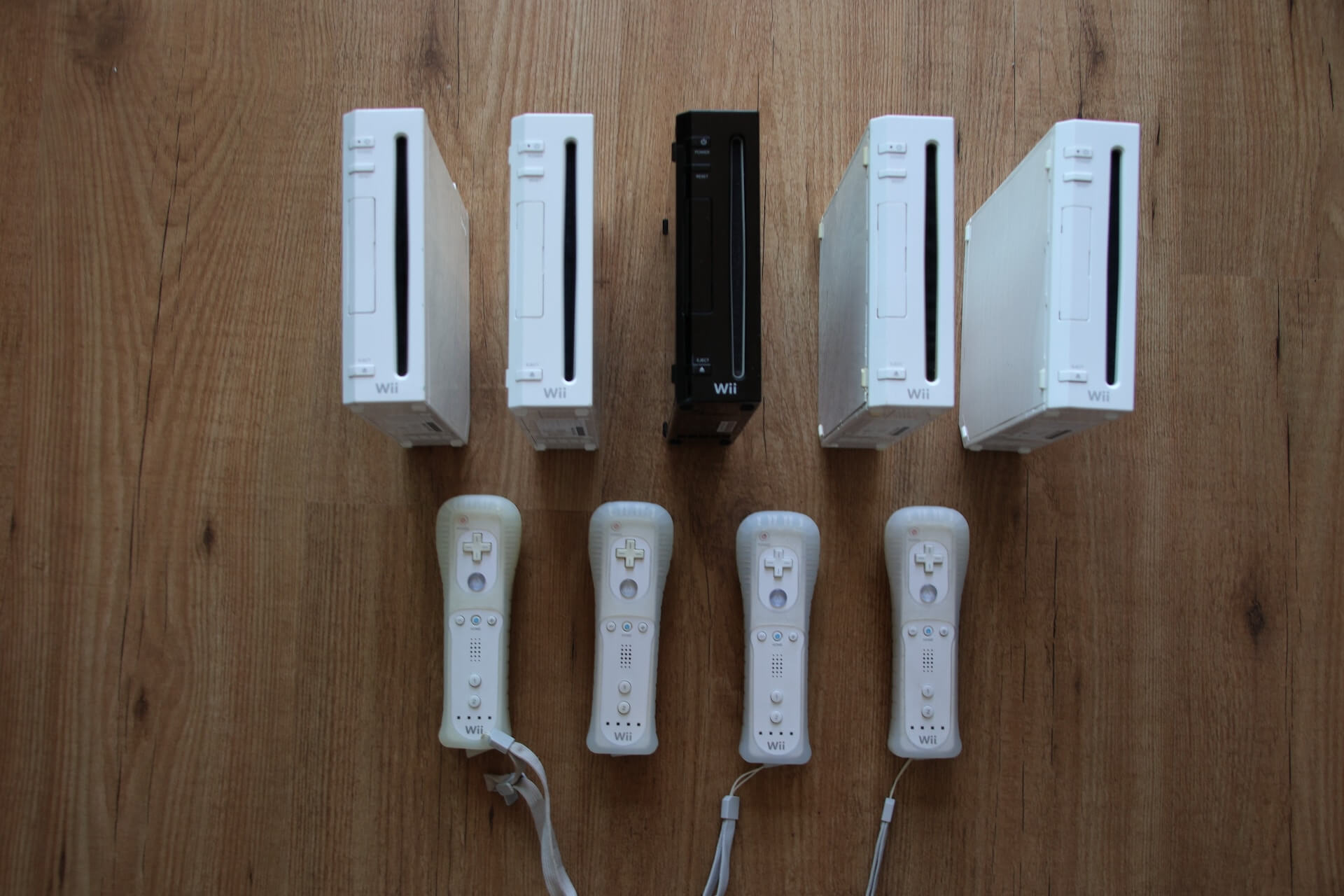Wii consoles and controllers rest on hardwood.