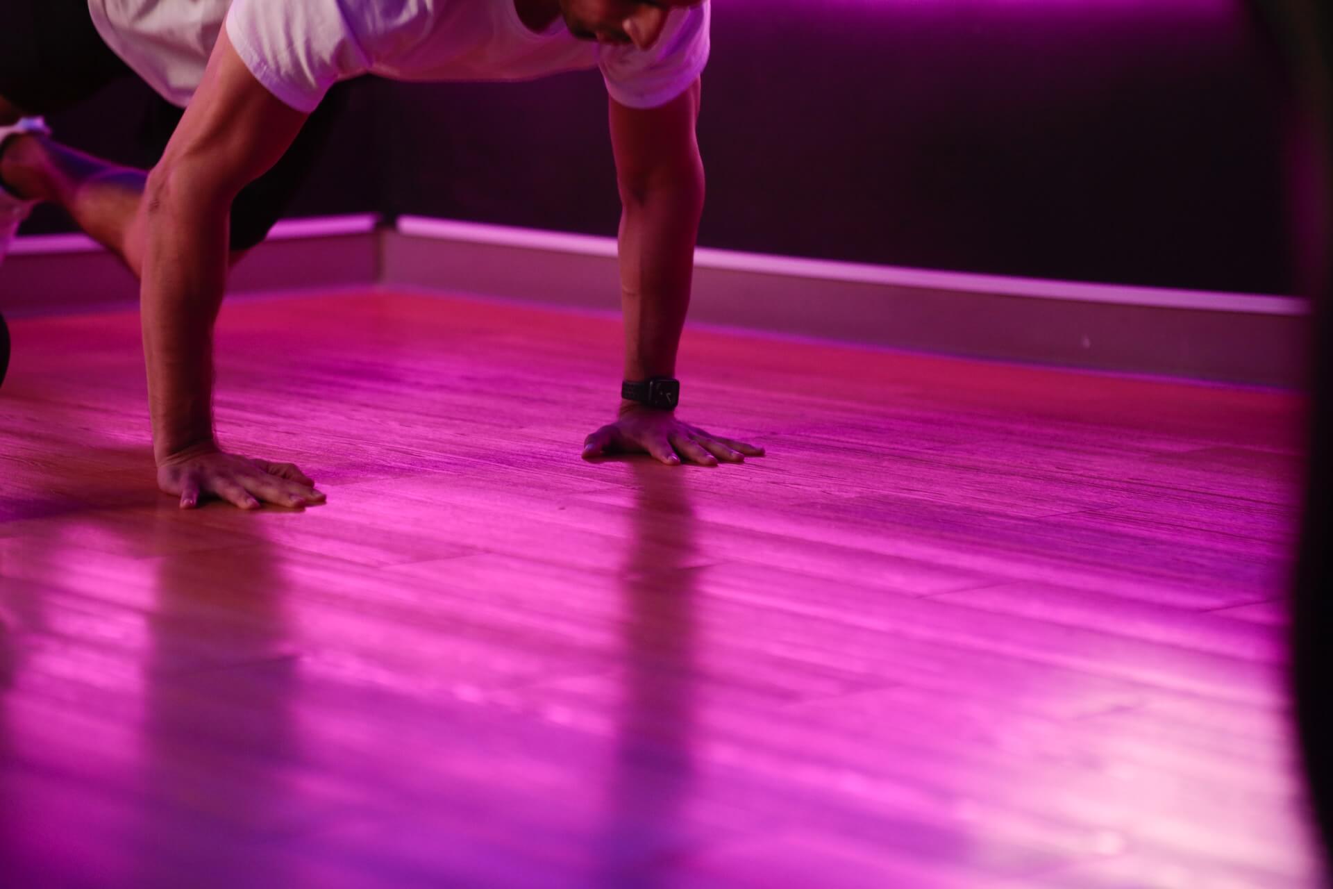 A man doing a burpee on a gym floor.