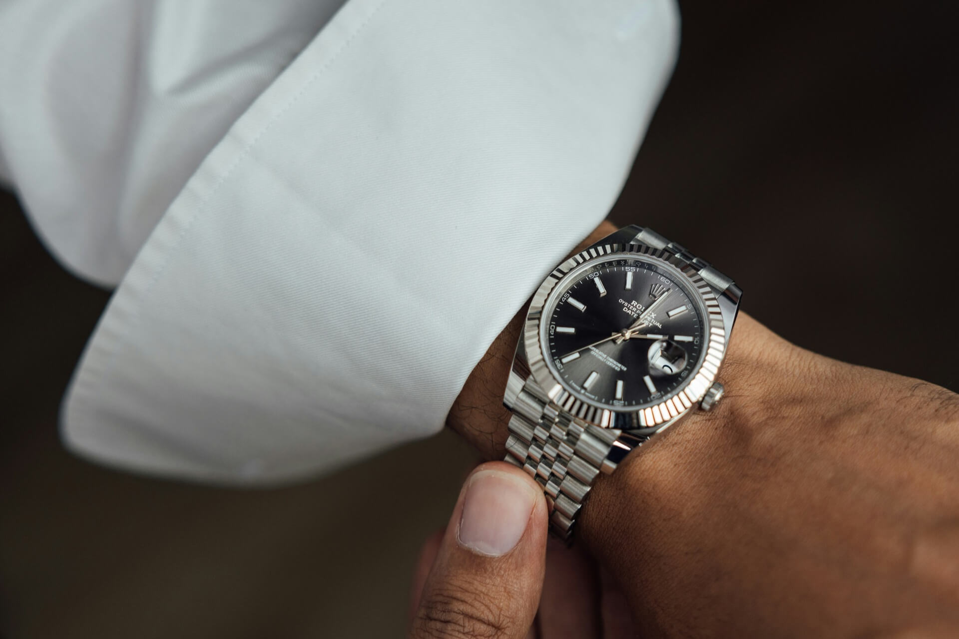 A man inspecting the Rolex he is wearing