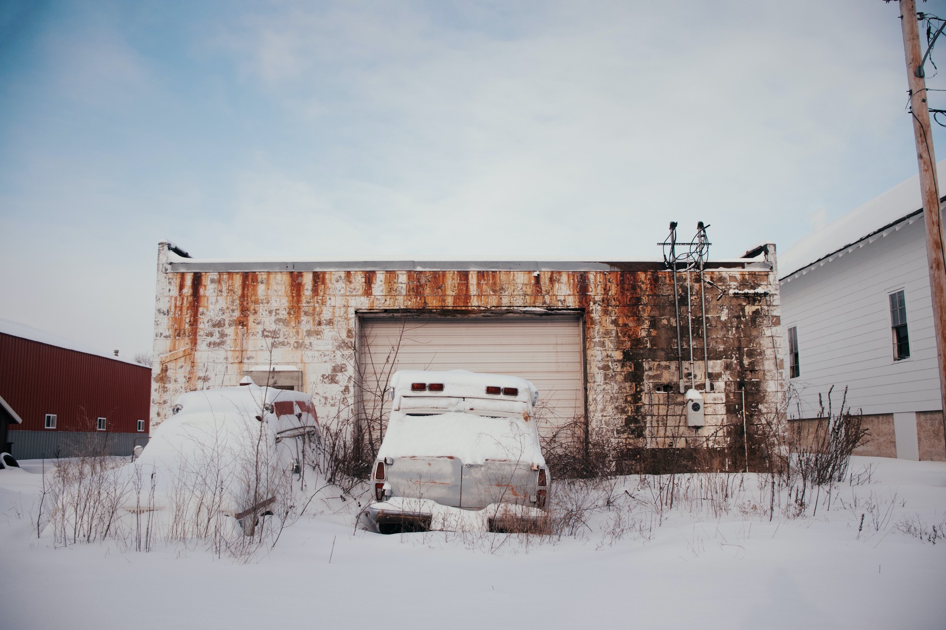 Snowed over cars in front of a garage
