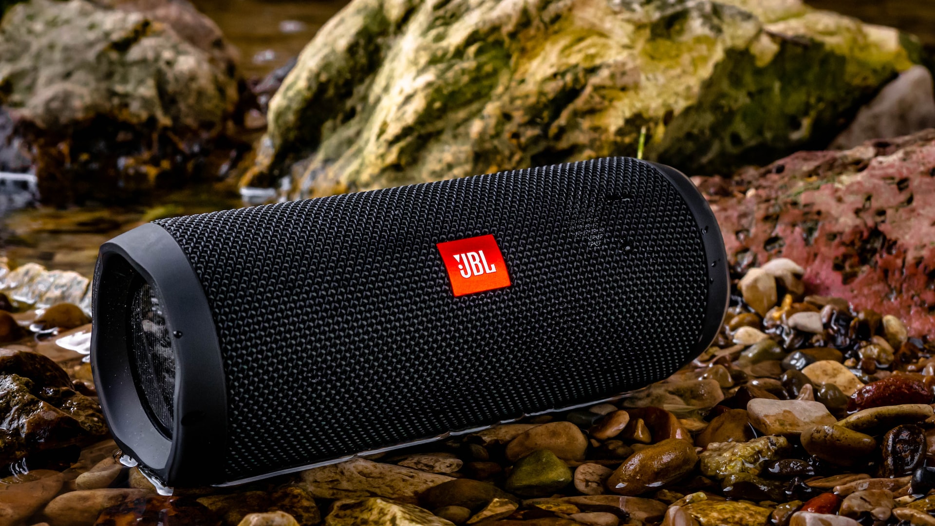 A JBL speaker outside on the rocks.