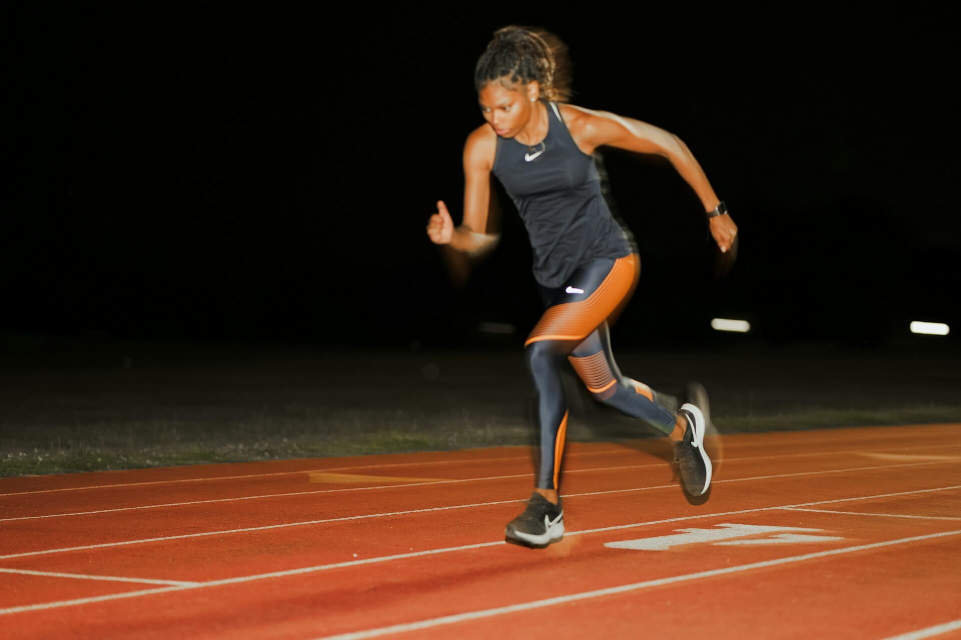 Woman running on a track at night