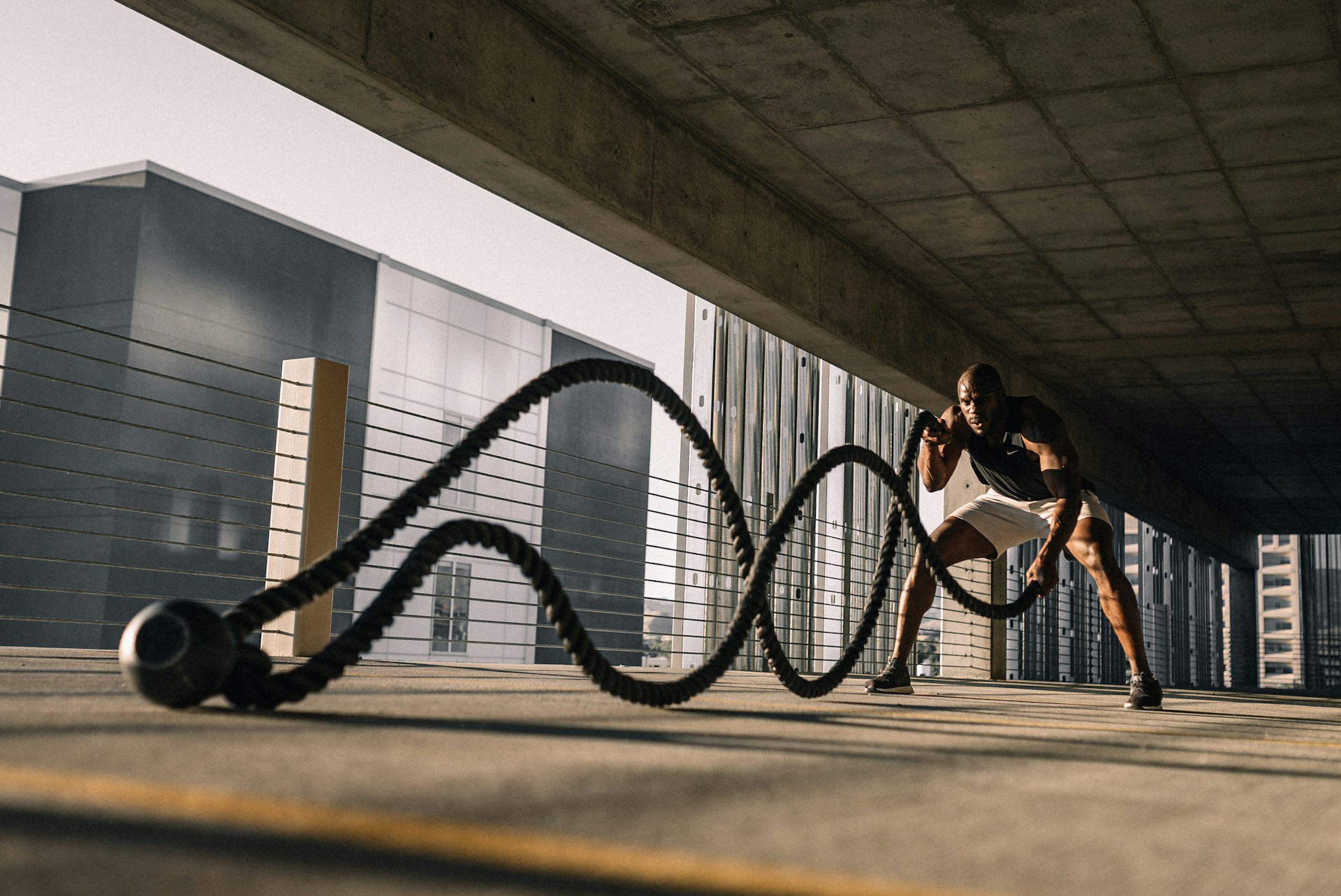 A man works out in a parking garage with weighted ropes, potentially following an AI fitness plan.