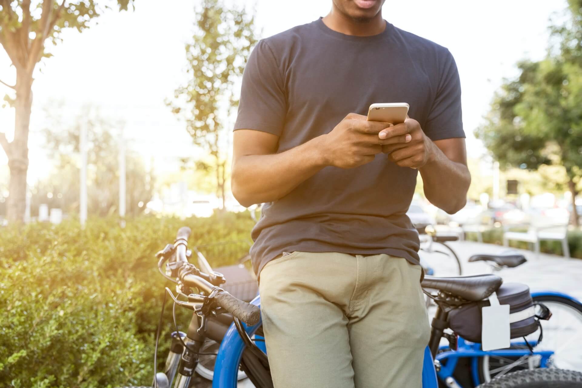 Man leaning on a bicycle while using his phone