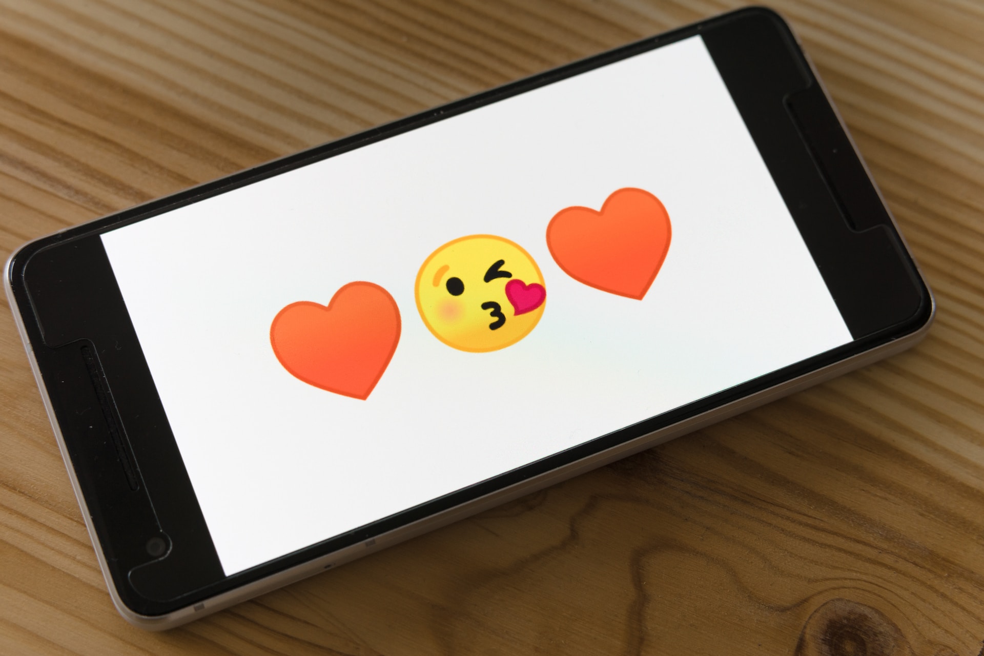 A phone showing heart and kiss emojis