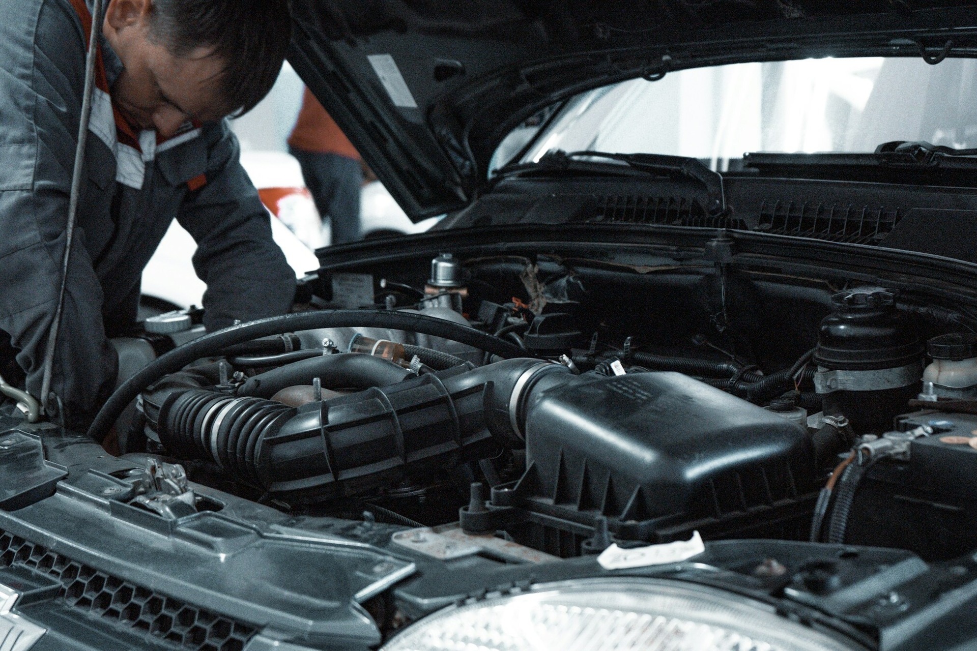 a mechanic working under hood of a car