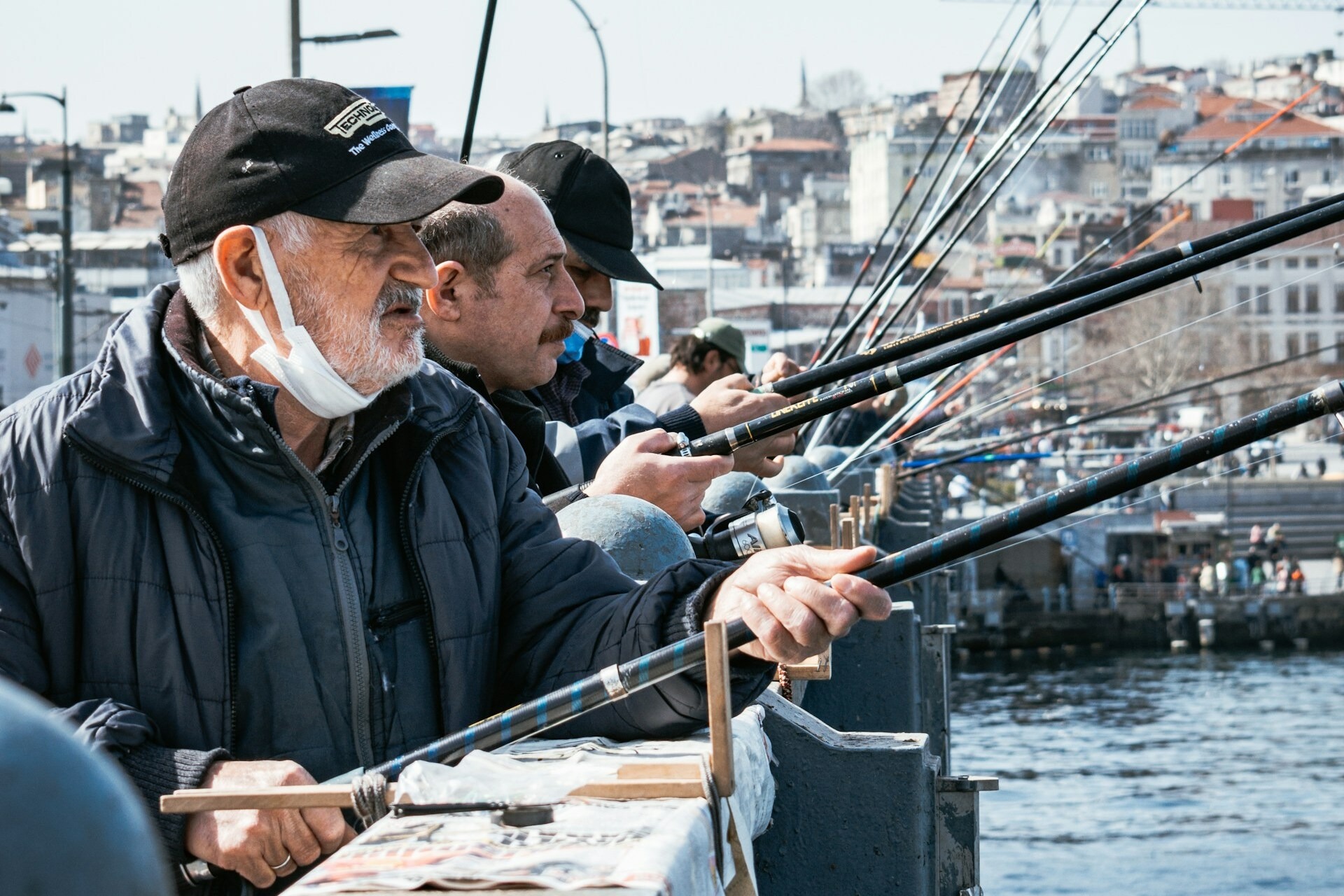 Group of elderly men fishing with rods.