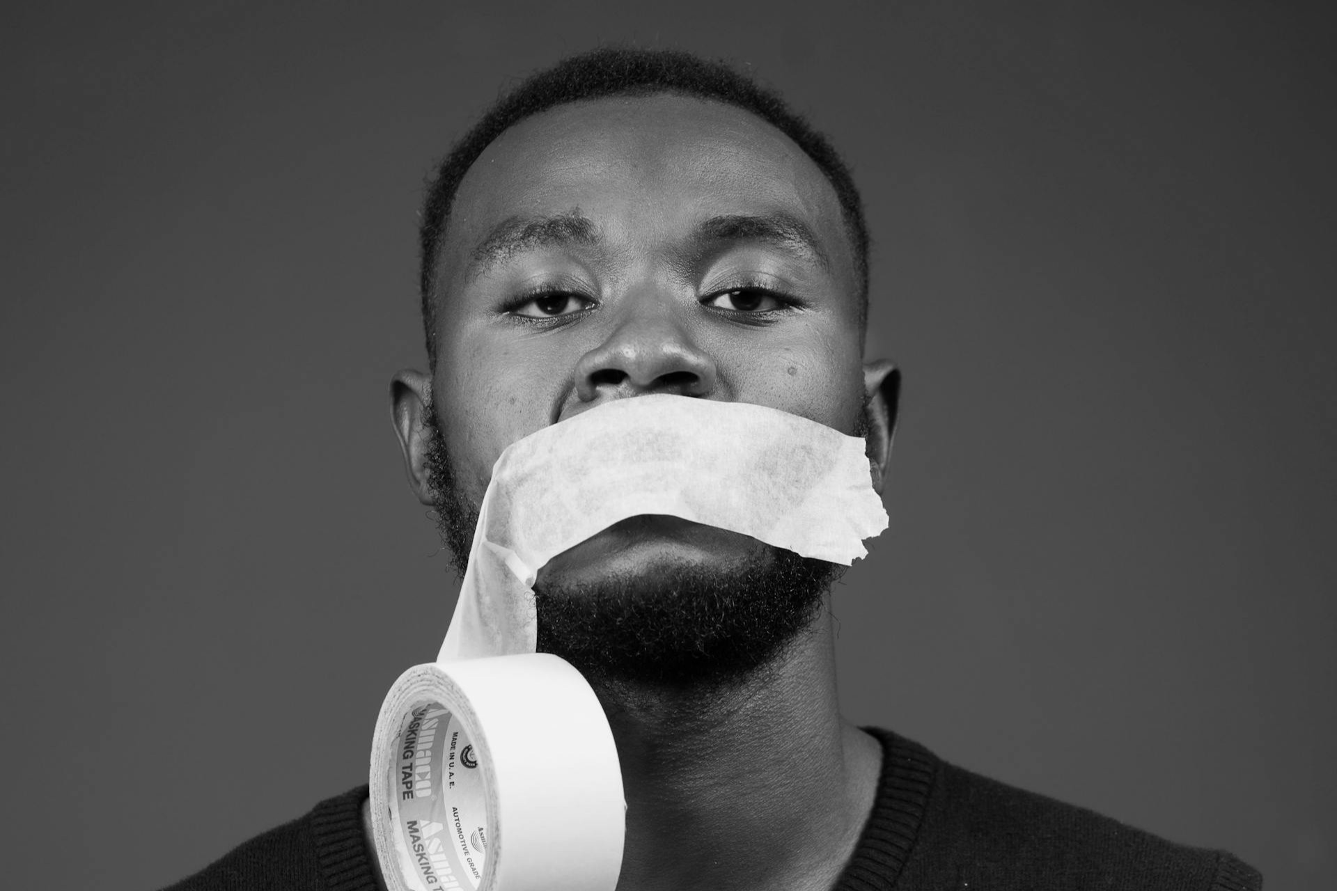 A man with a roll of tape over his mouth