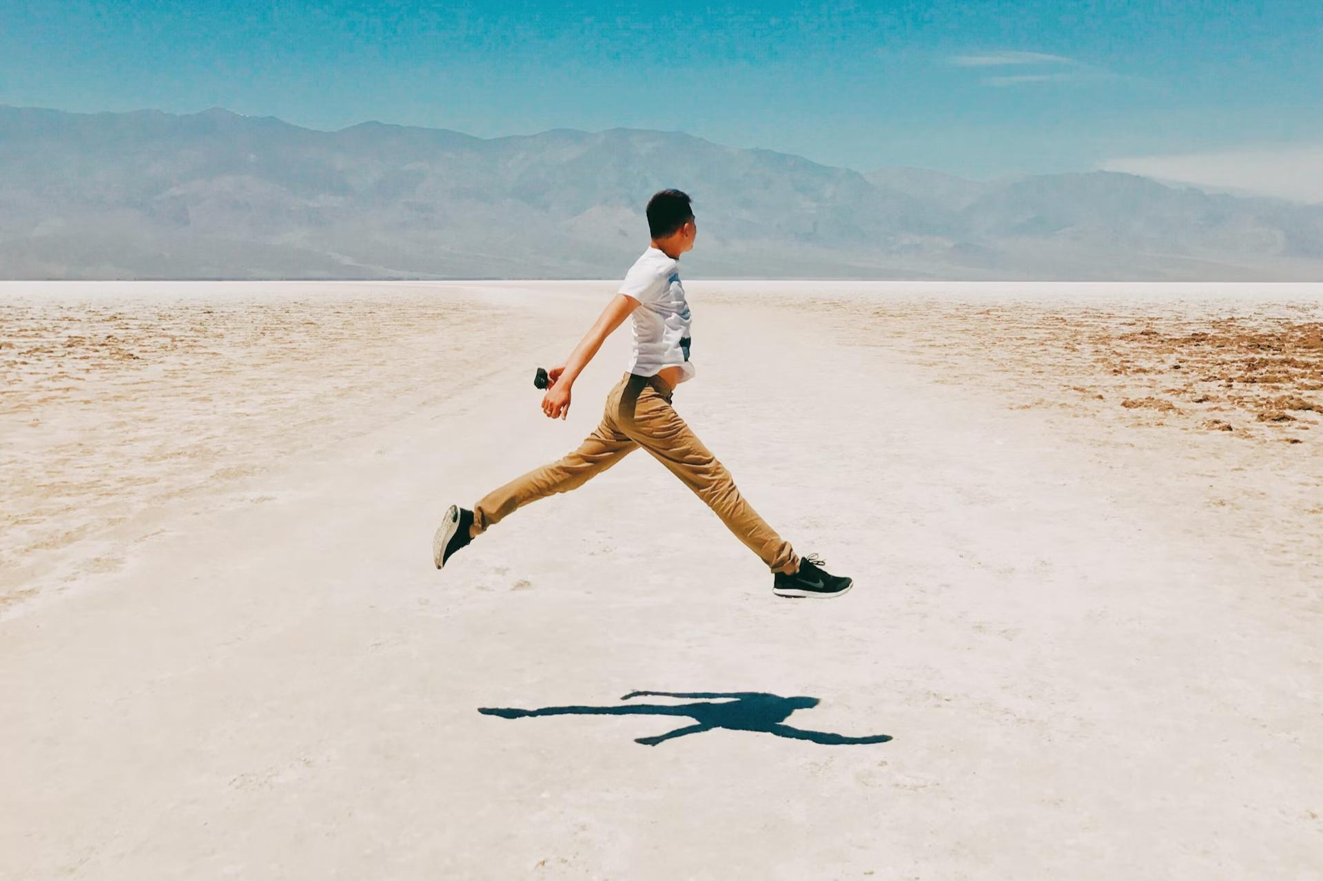 man in desert jumping on road