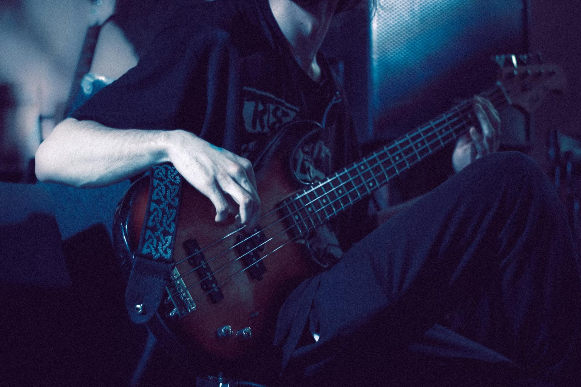 person in black playing bass guitar