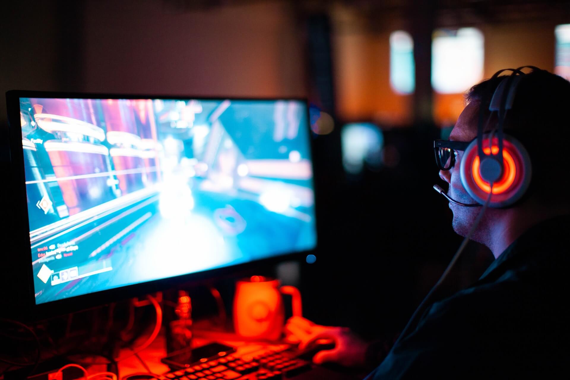 A man with a headset playing a video game on a computer