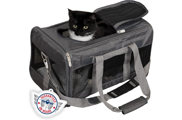 A black and gray mesh soft pet carrier sits against a white background. It has two short handles and one long shoulder strap. A black and white cat sits inside it with their head peeking out through the top zippered door. A Guaranteed On-Board symbol is on the lower left corner.