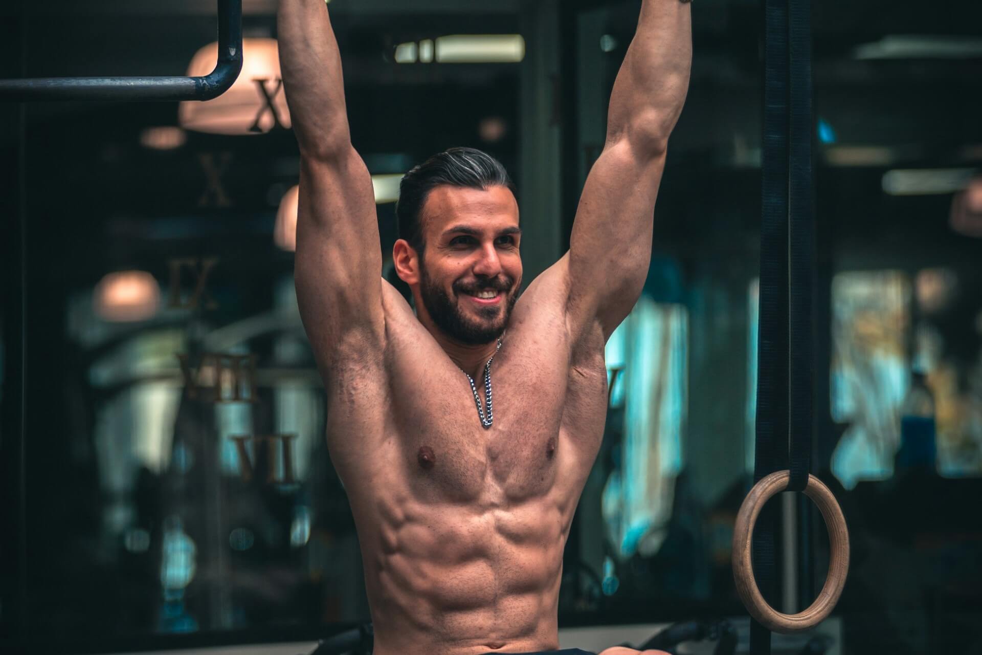 A smiling man doing a dead hang