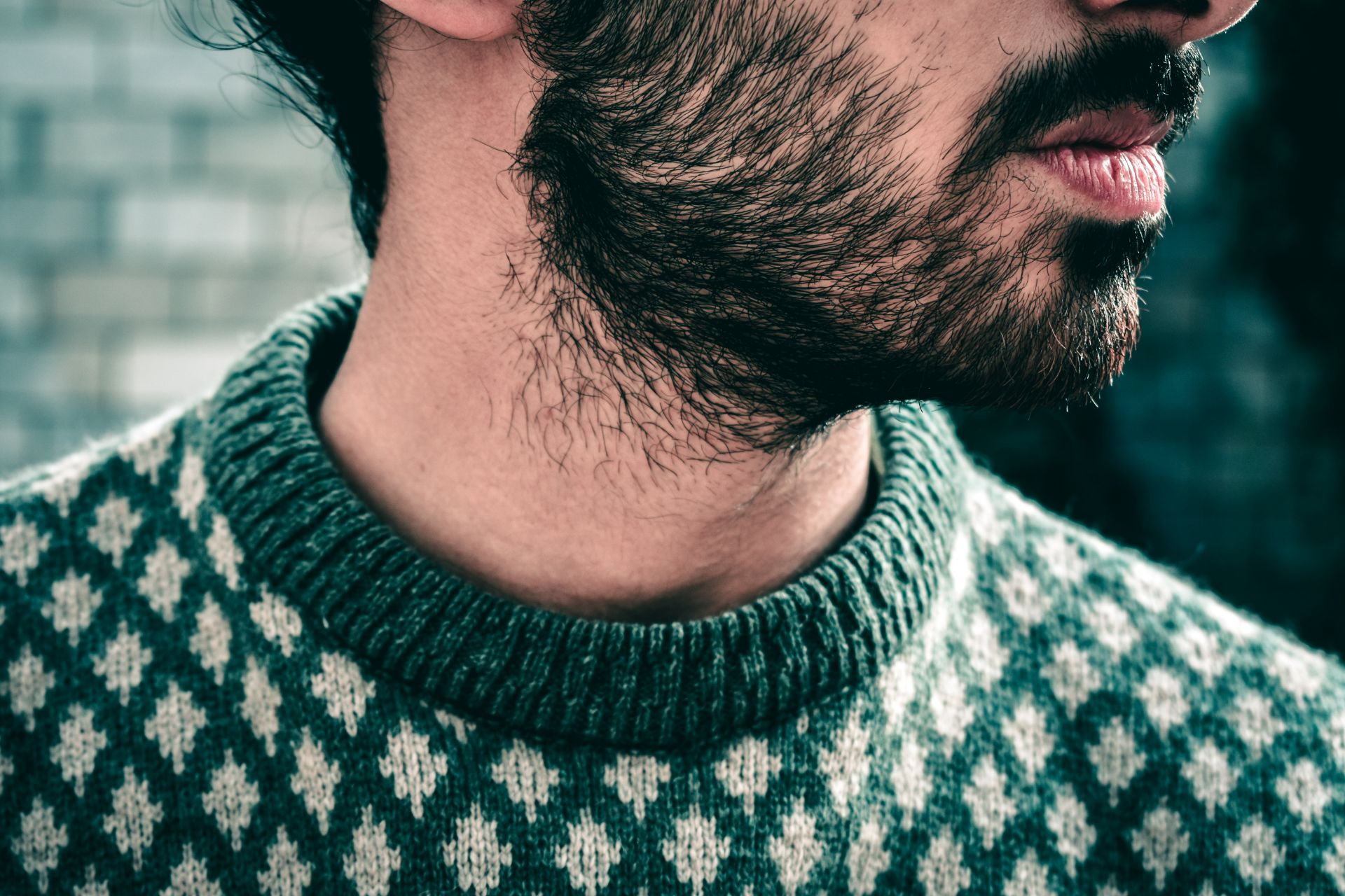 Side view of man in green sweater with beard.