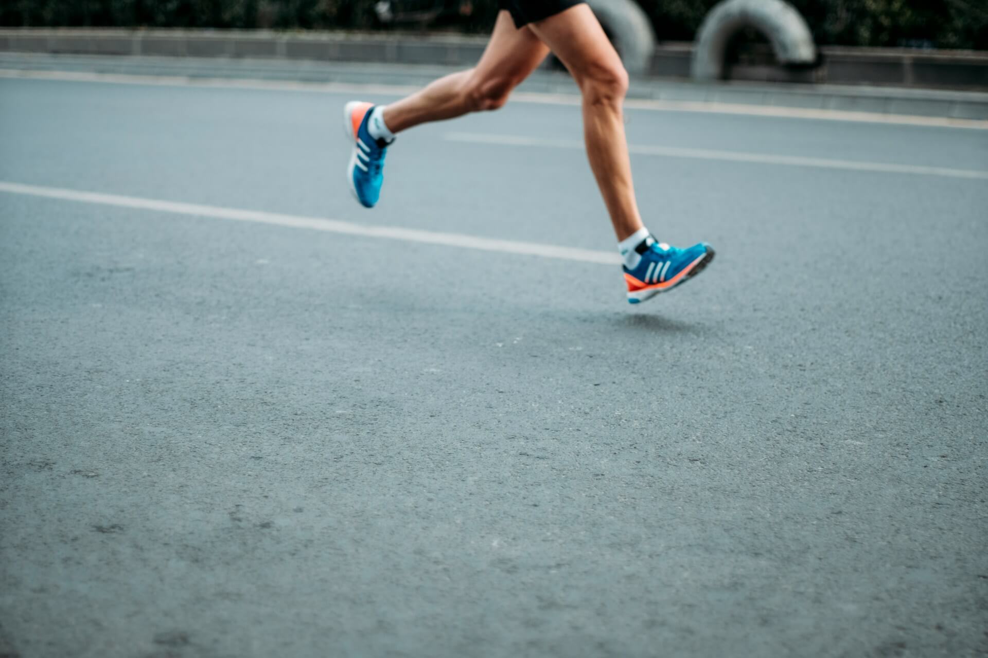 Person running a race with blue and orange Adidas shoes