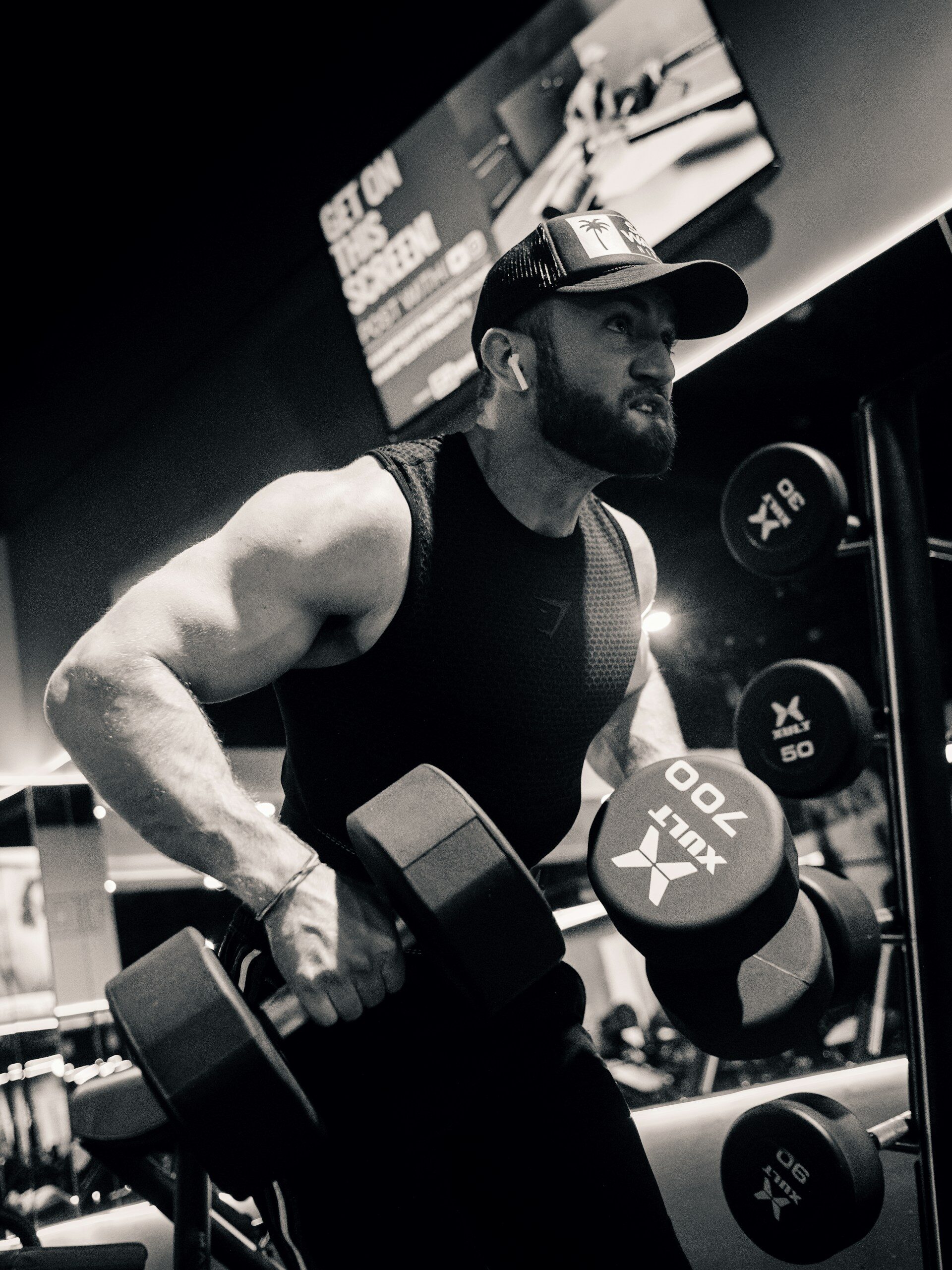A black-and-white photo of a man lifting dumbbells.