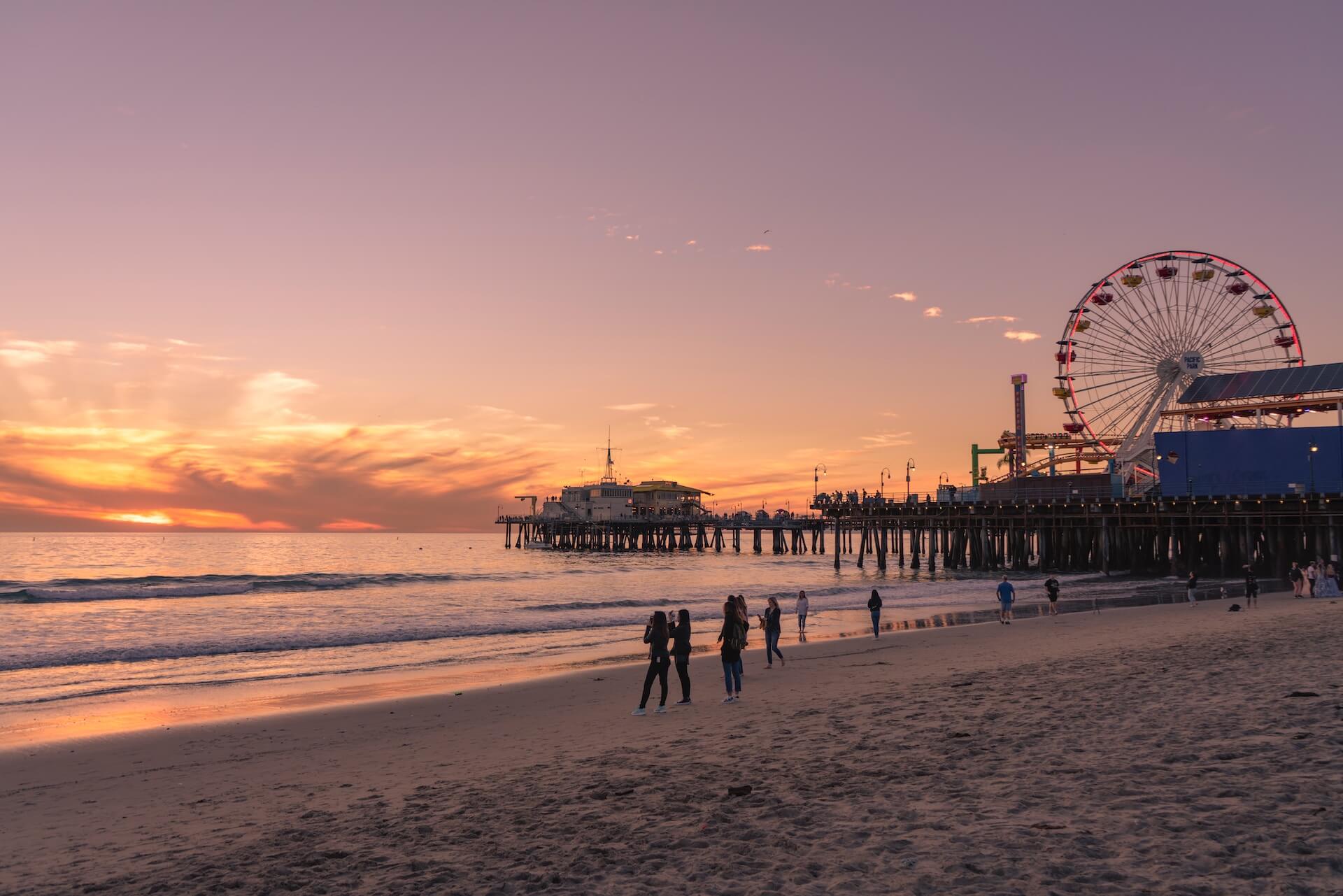 People walking on Santa Monica beach next to the pier.