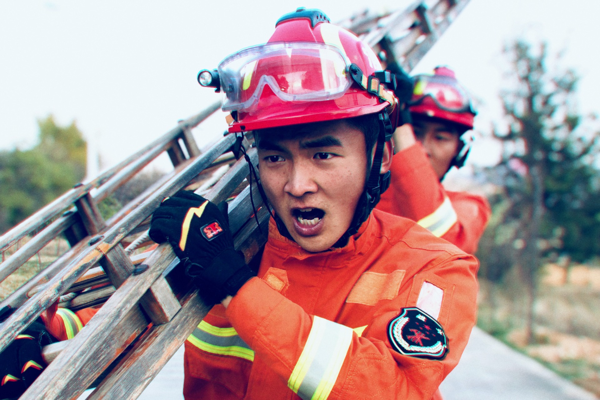 Two determined firefighters carry a ladder.