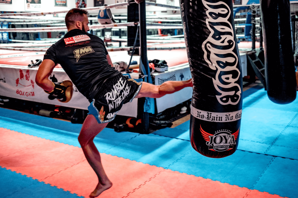 An MMA fighter kicking a hanging punching bag