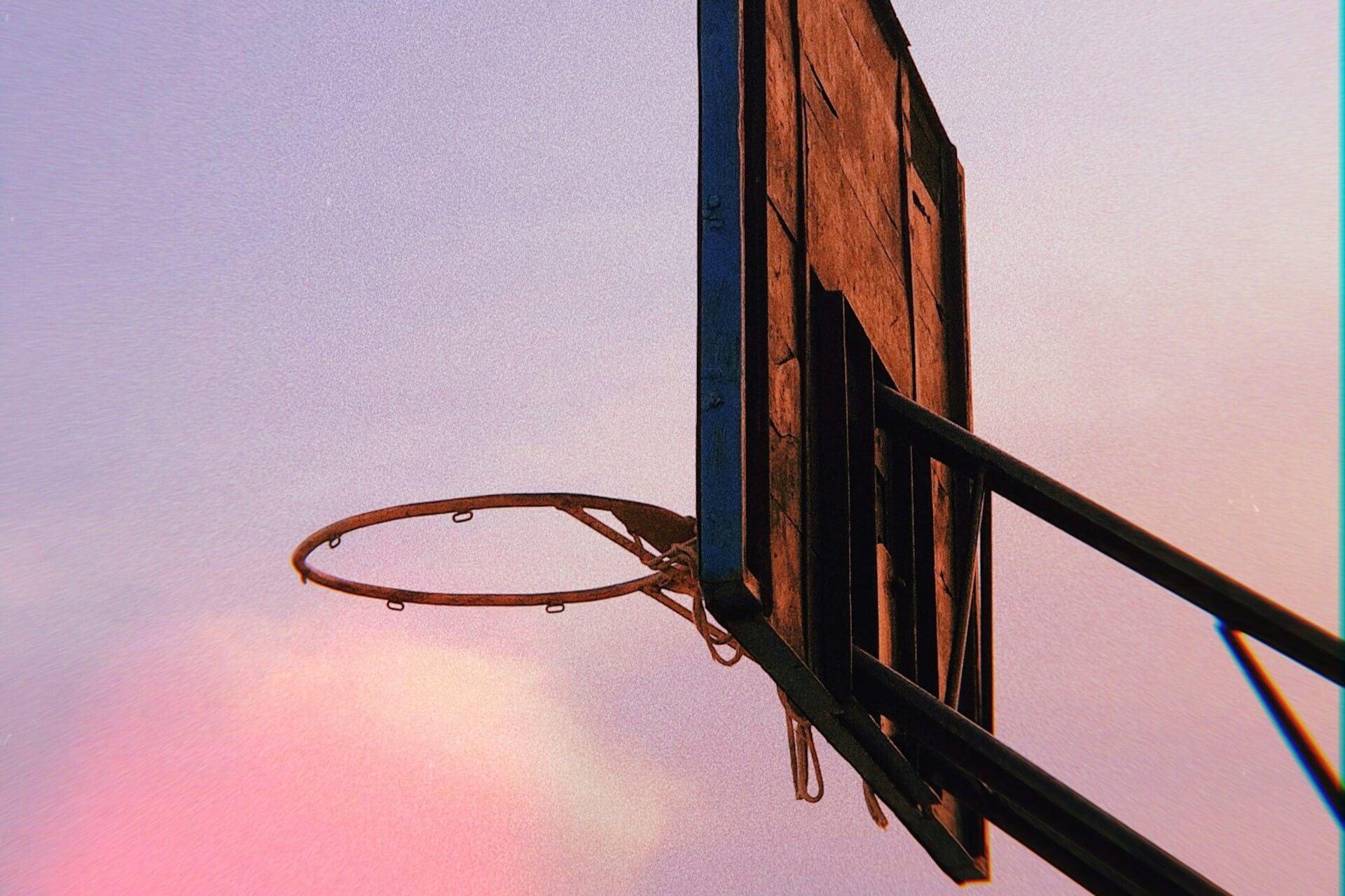 a basketball ring with a damaged net during sunset