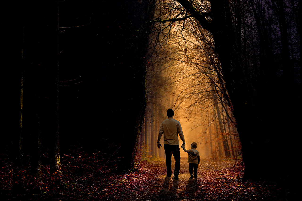 A father and child walking in a forested area
