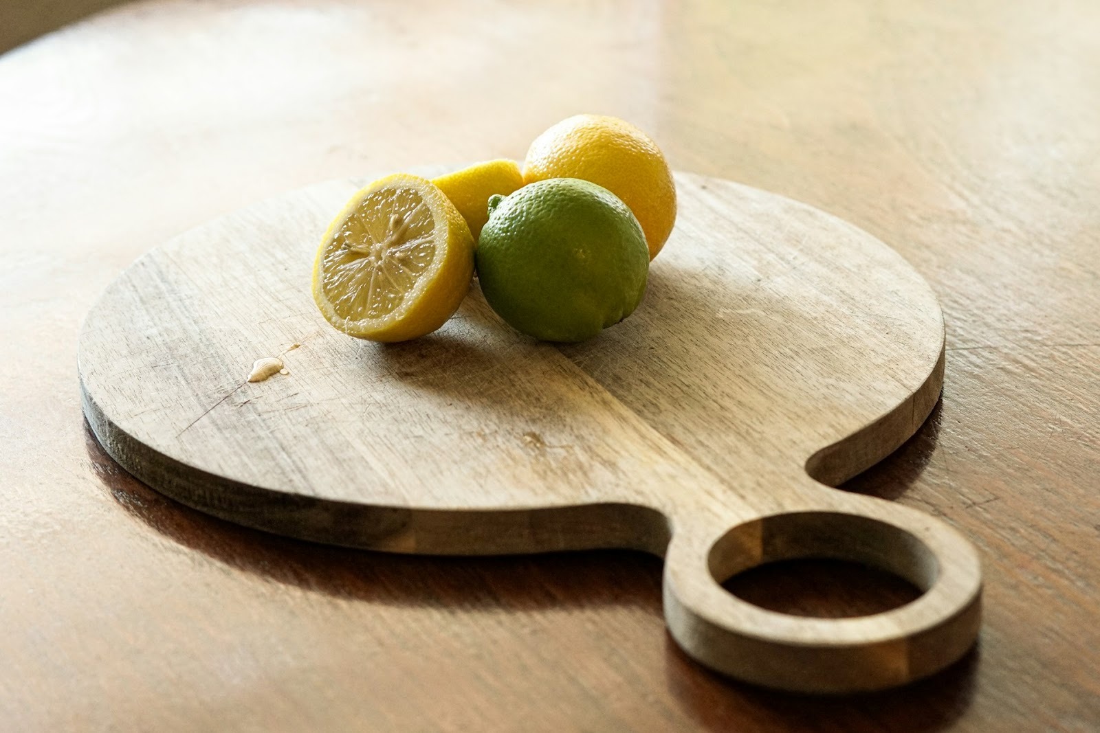 a group of lemons and limes on a cutting board