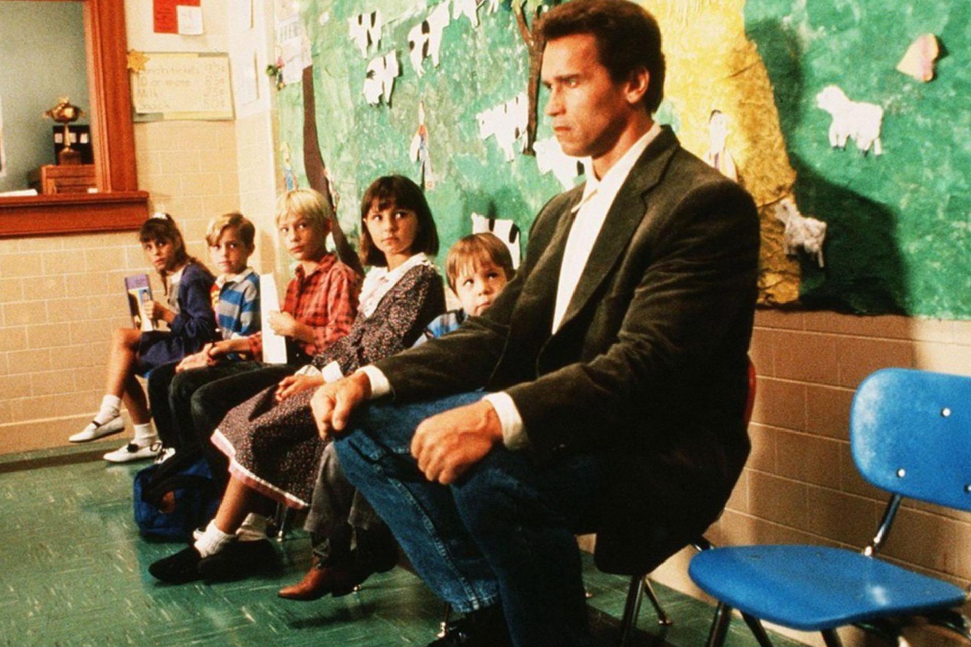 Man in jacket sitting on chair with kids watching him