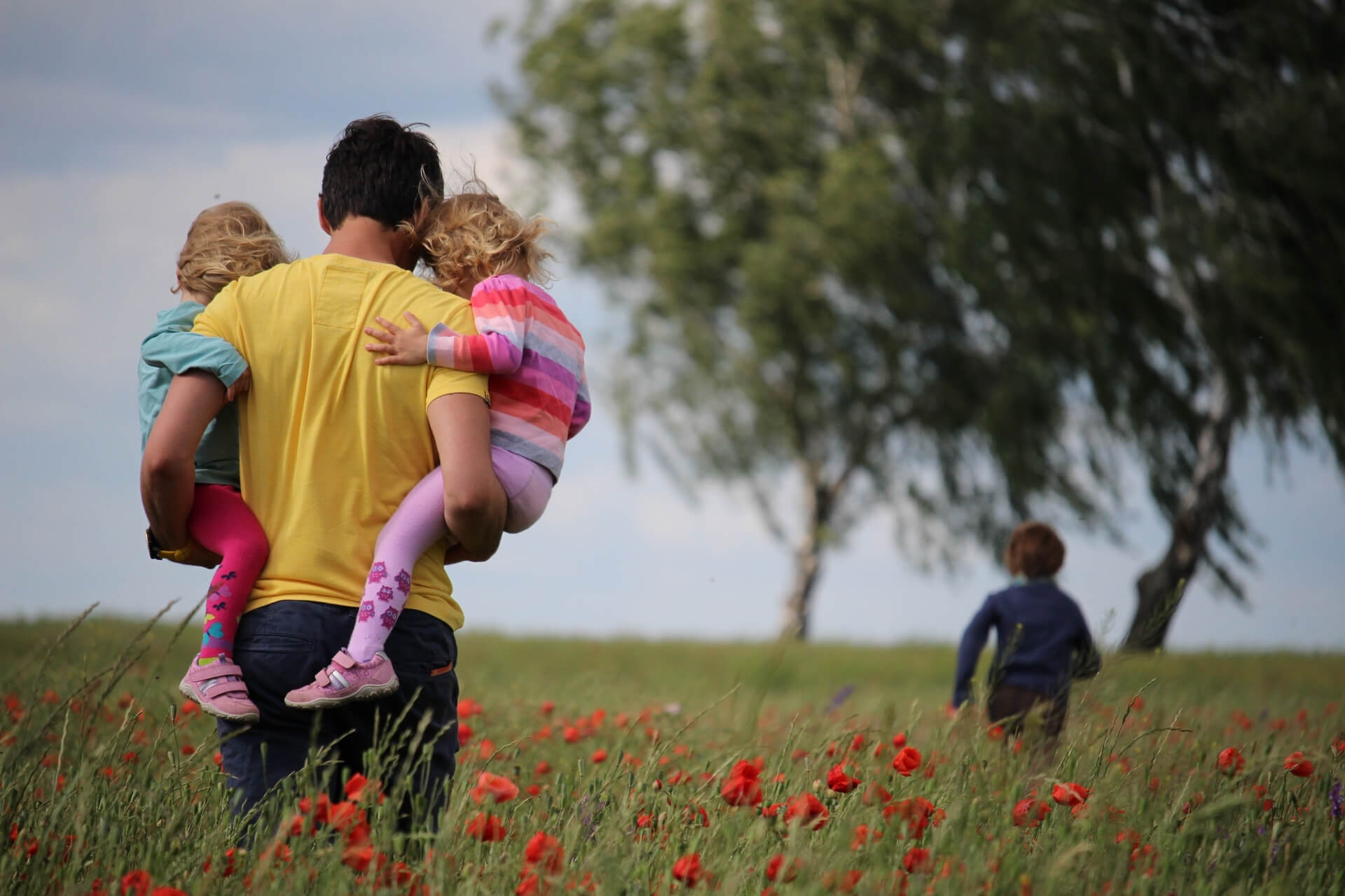 dad holding two children in a flower field