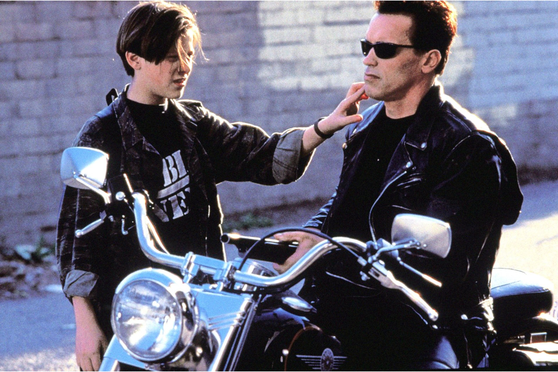 Boy touching face of man wearing sunglasses on bike