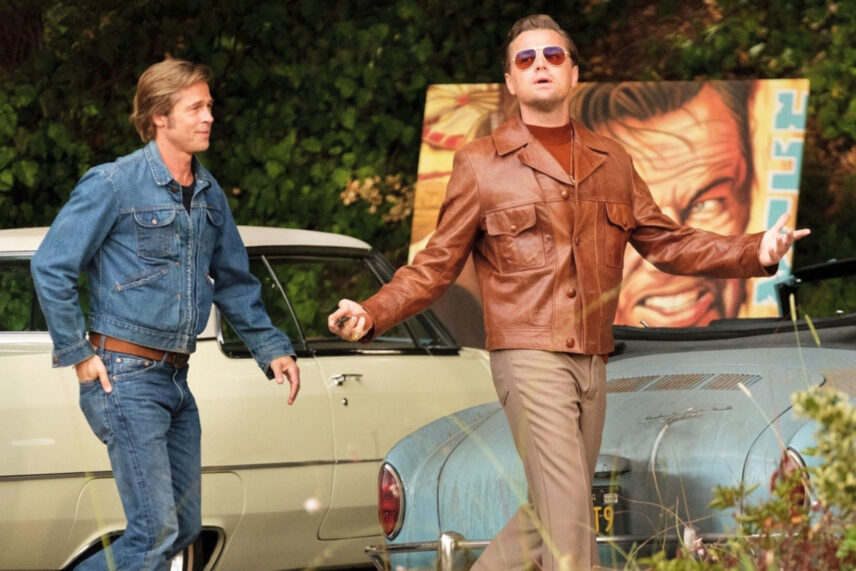 two men walking past cars