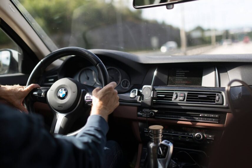 A person holding the steering wheel of an old BMW