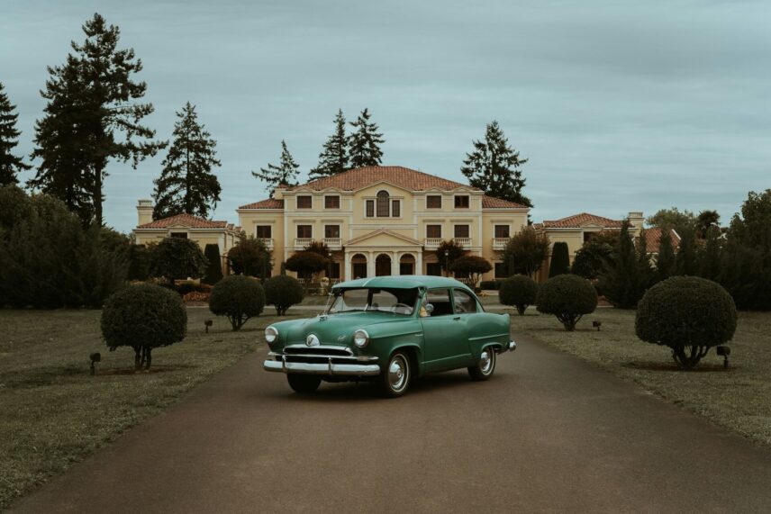 A green vintage car in front of an old home