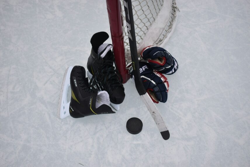 Overhead view of hockey skates, gloves, stick and puck next to goal on the ice