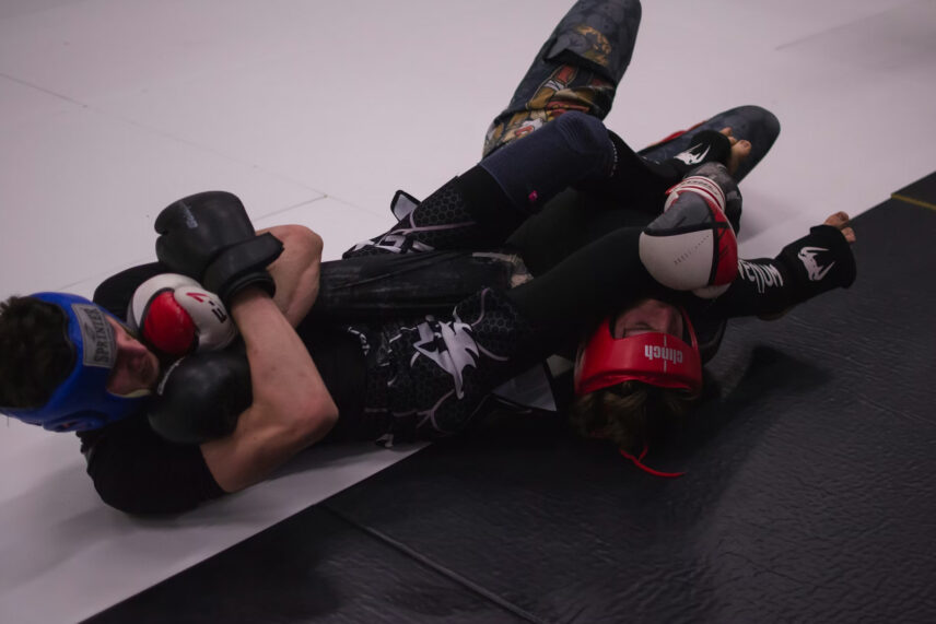 man in red headgear wrestling man in blue headgear