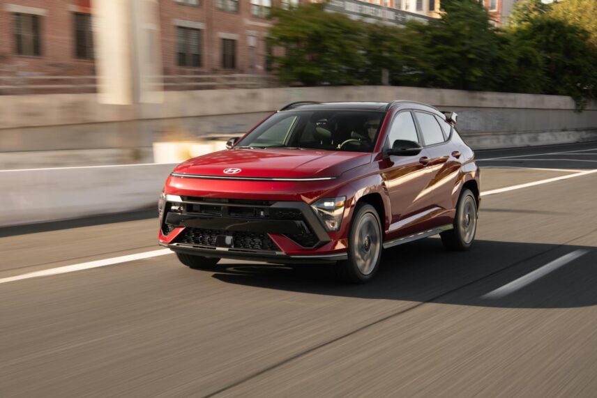red car driving on road past buildings