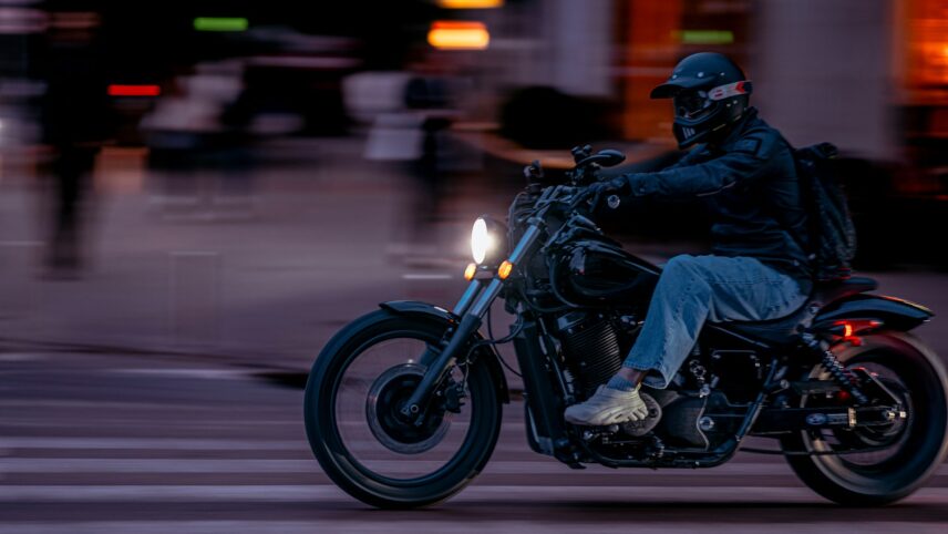 A motorcyclist rides along a city street at night