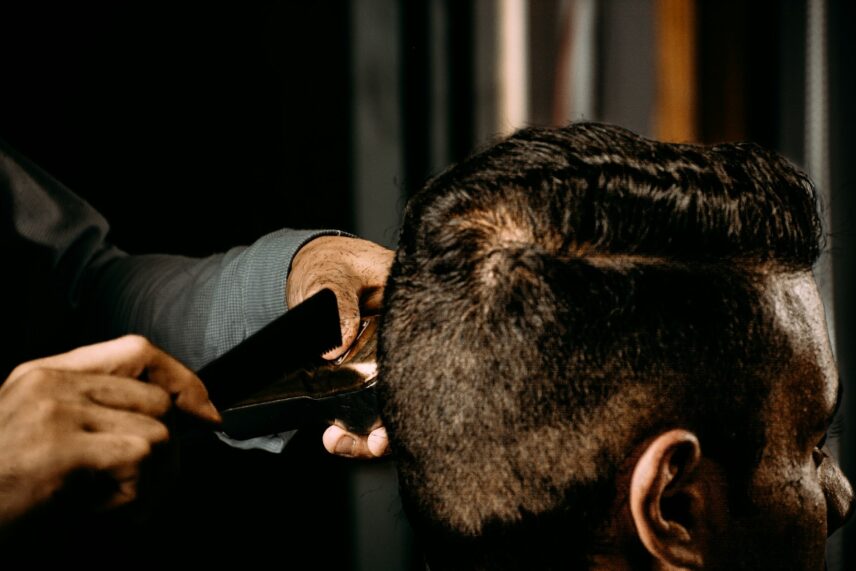 A closeup of a man's hair int he barber. His head is starting to have some hair loss in the middle