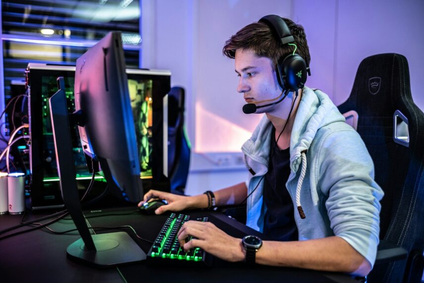 A man on a PC with a headset, keyboard and mouse.