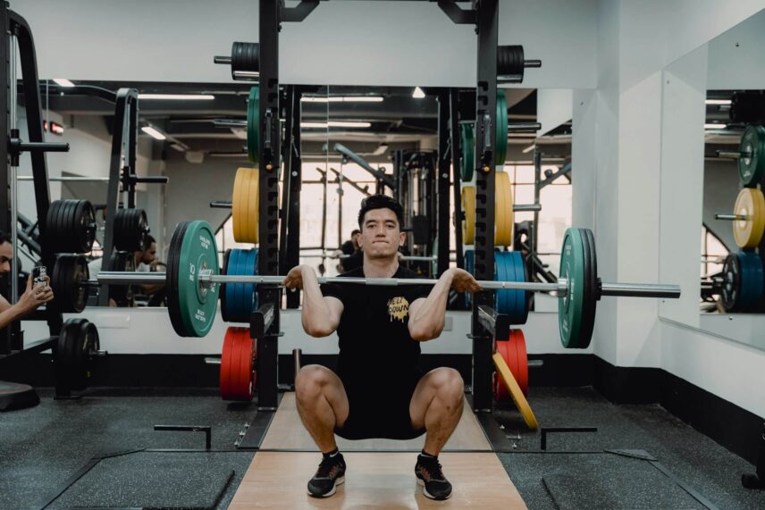 Man doing squats on a squat rack in a gym
