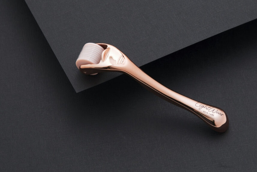 A rose gold derma roller against a black background
