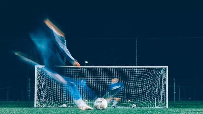 Blur of person kicking soccer ball at goal