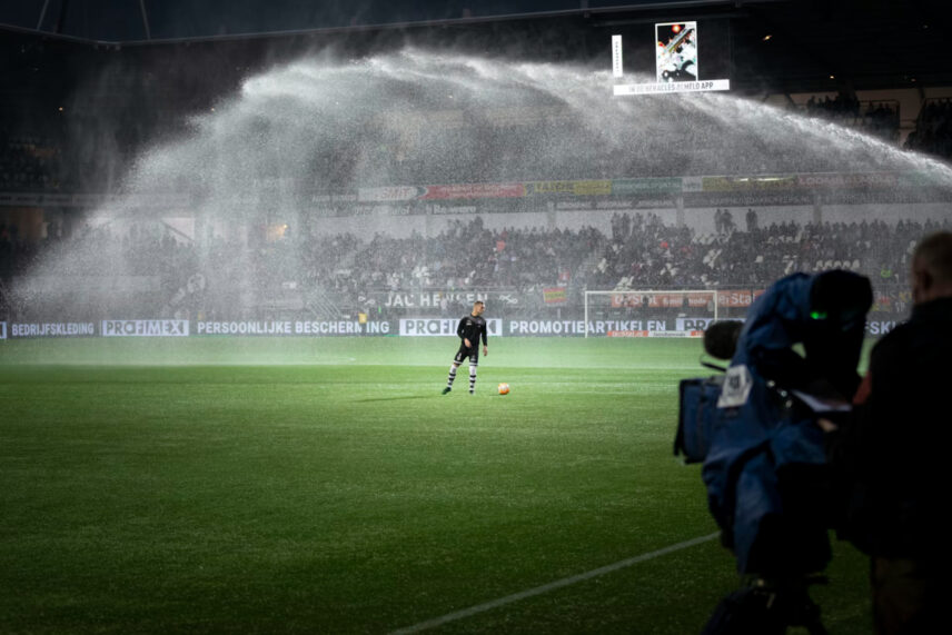 Man in black with ball under sprinklers