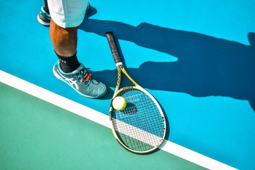 person standing next to a tennis racket and ball
