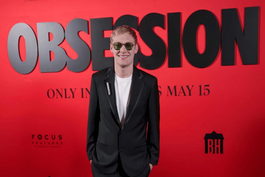 Director Curry Barker stands in front of a red promotional backdrop for the 2026 horror film Obsession