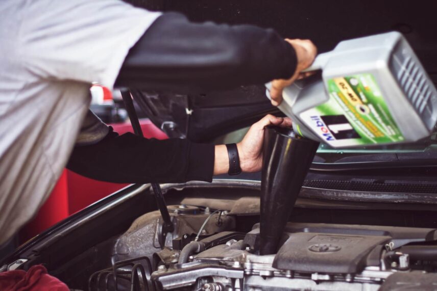 a car mechanic pouring a fluid into a Toyota engine