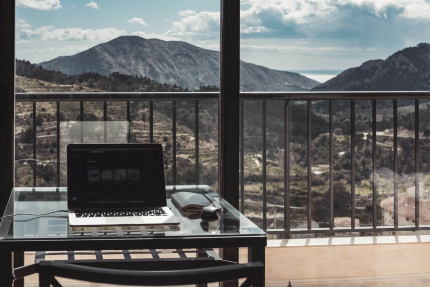 MacBook laptop on a wooden table with mountain views in the background